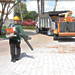 Crew member cleans up a driveway with a leaf blower